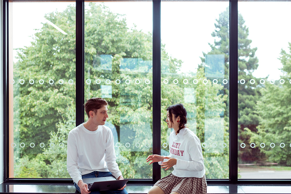 Students talking sitting in front of a window