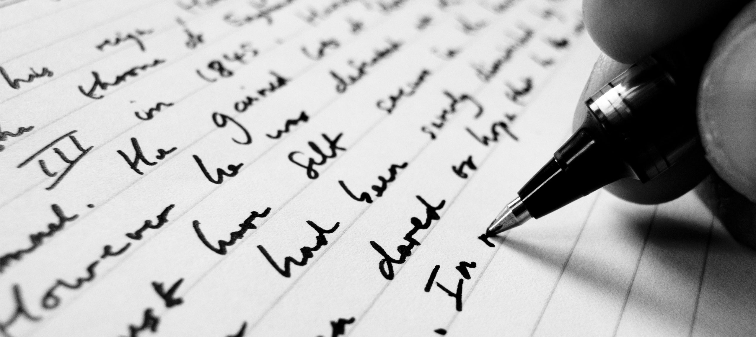 Stock photo of a pen writing in blank ink on ruled paper