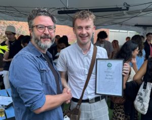 Ellis Quinn receiving the Paddon Prize certificate from David Salas
