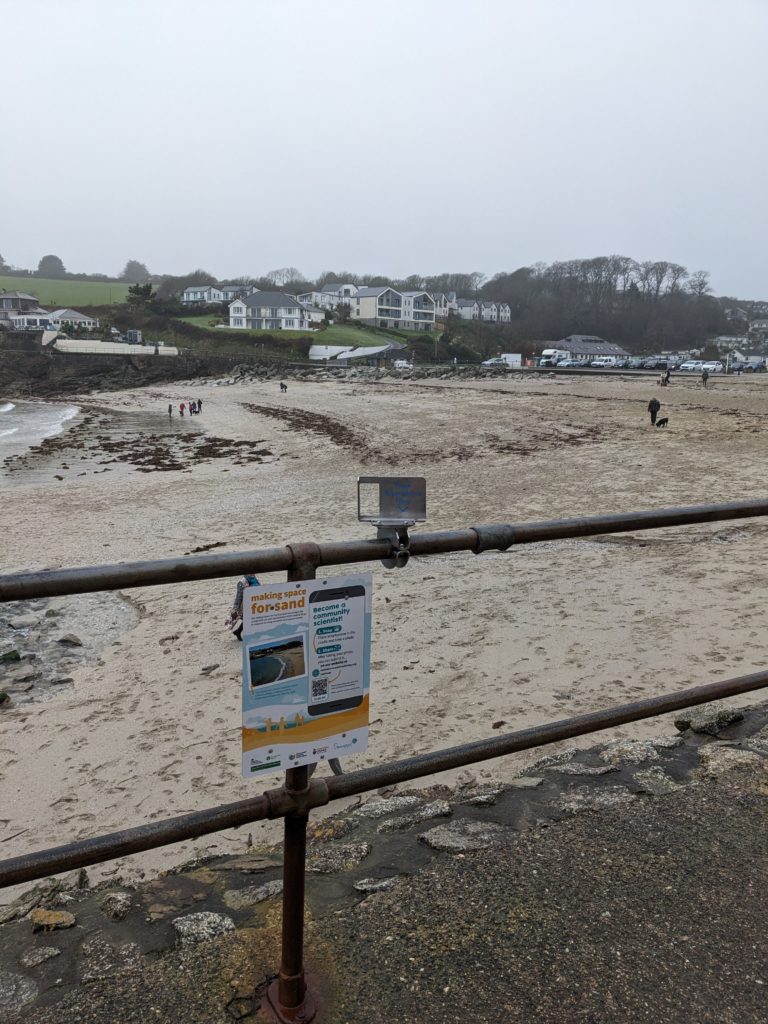 A metal cradle for a mobile phone attached to the railings at Swanpool beach in Falmouth. 
