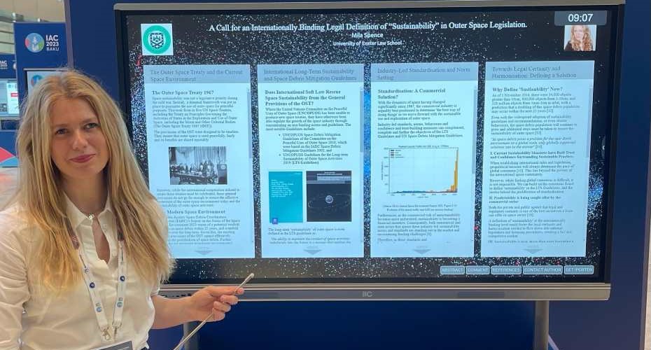 Student Mila Spence stood in front of a display screen which shows her paper she presented at the conference