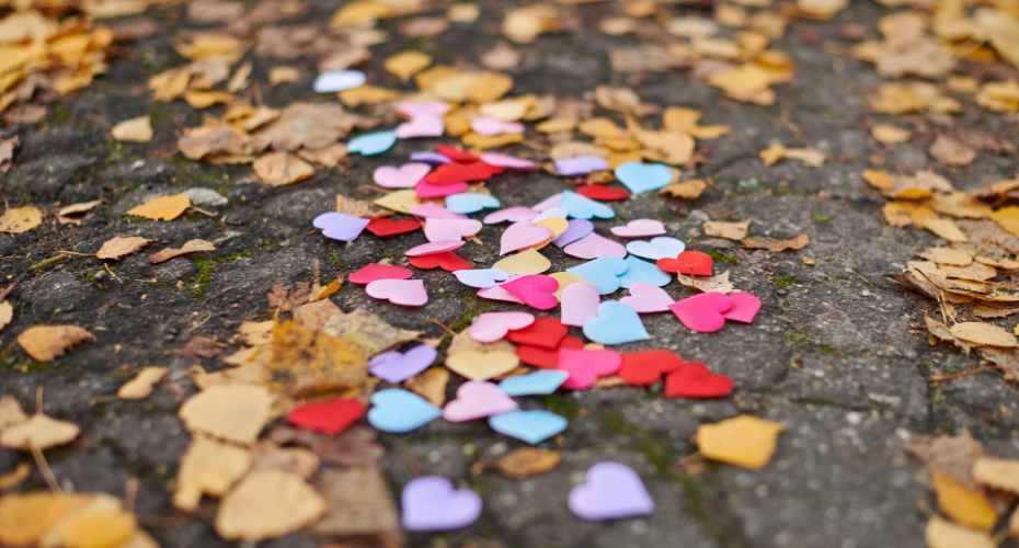 a photo of scattered leaves and multi coloured paper heart confetti