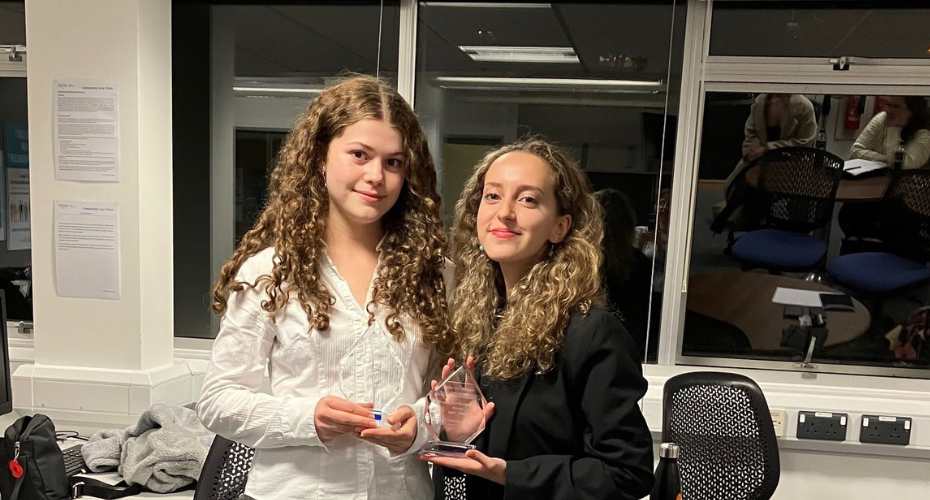 Two students holding the winning trophy of the negitiation competition 2023