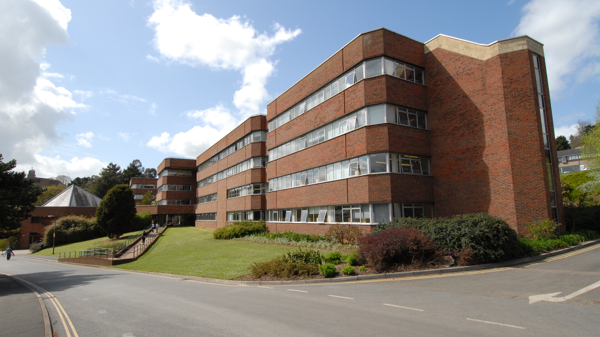 A sideview of Amory building on Streatham campus. Blue sky and white clouds in the background of this brick and glass building.