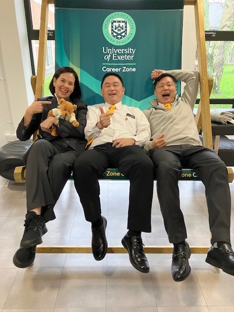 Three people from the Thai visiting group sat in an oversized University of Exeter deckchair