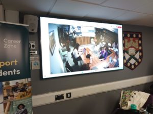 the large screen in the Moot Court with the Exeter Shield to the right.