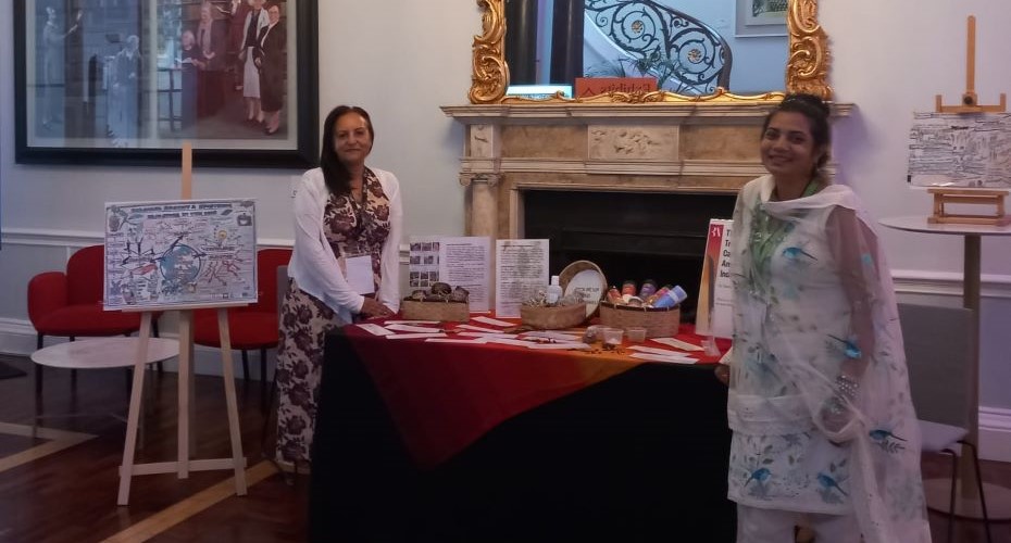 Two people stood either side of a display table and in front of an old fireplace.