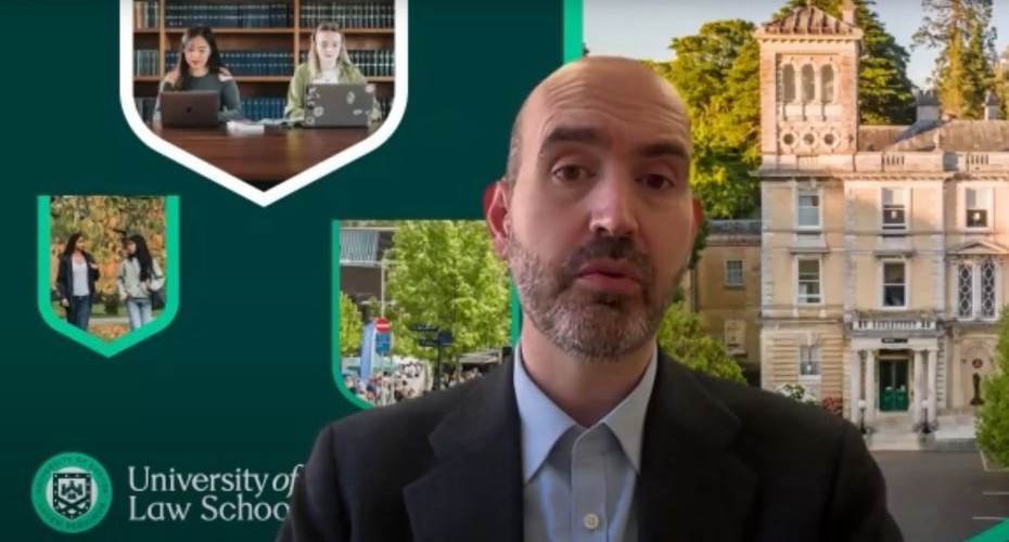 Professor Sergakis presenting an online meeting with a University of Exeter backdrop featuring images of the campus, displayed in shield shapes and the University logo. Professor Sergakis is wearing a collared shirt and jacket.