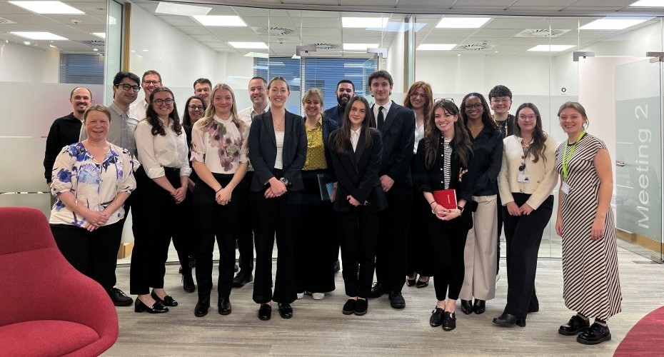 a group of students, staff and people from Foot Anstey stood together in front of glazed meeting room.