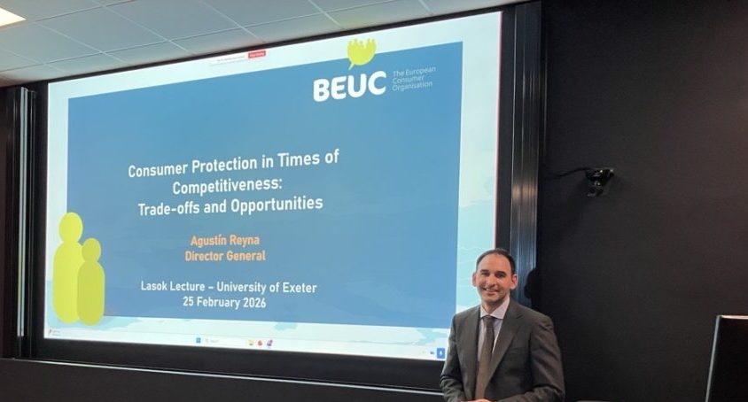 Dr Agostin Reyna stood in front of a large display screen just before he delivers the lecture. He has his hands together and is smiling at the camera