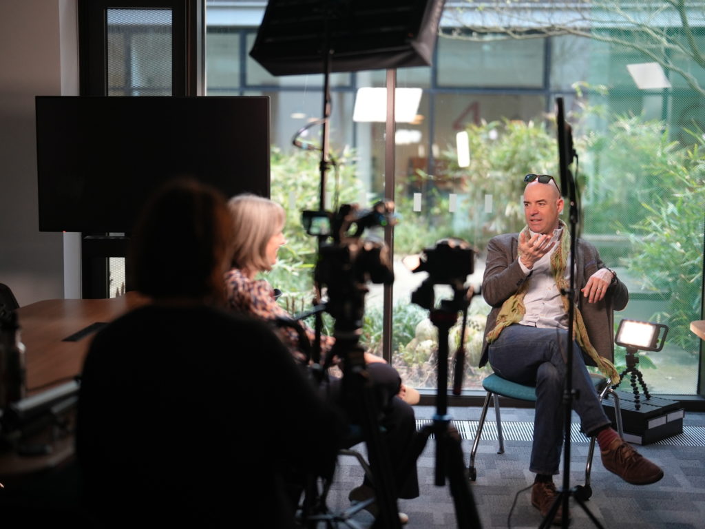 A man being interviewed behind a camera.