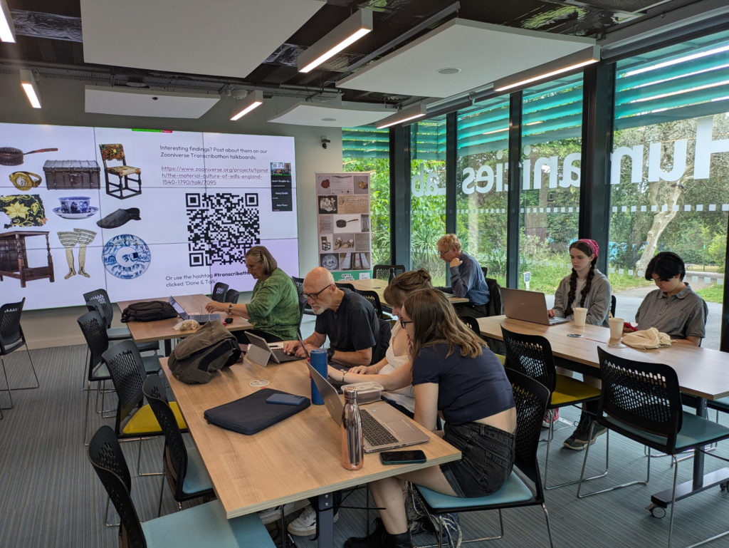 A group of people on laptops in front of a screen.