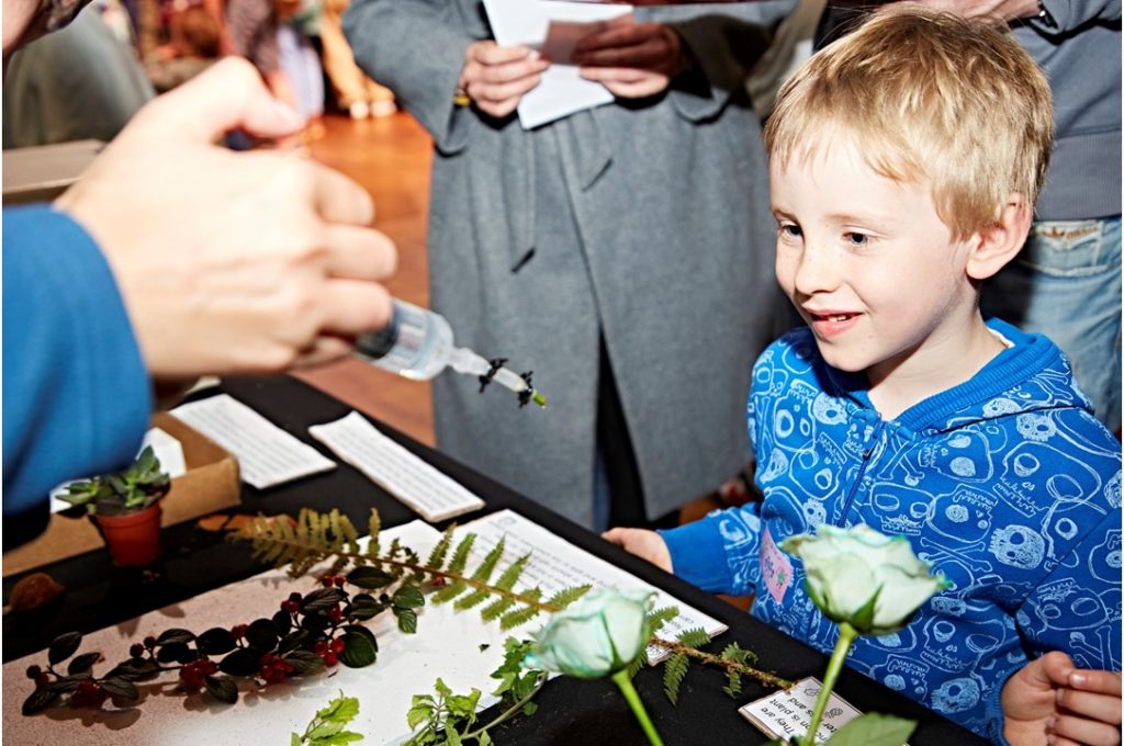 A child looking at a table covered in paper and plant leaves
