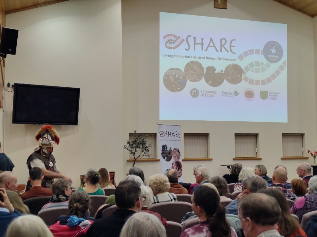 People seated waiting for the talks to start. Someone dressed as a Roman soldier is speaking to the front row.