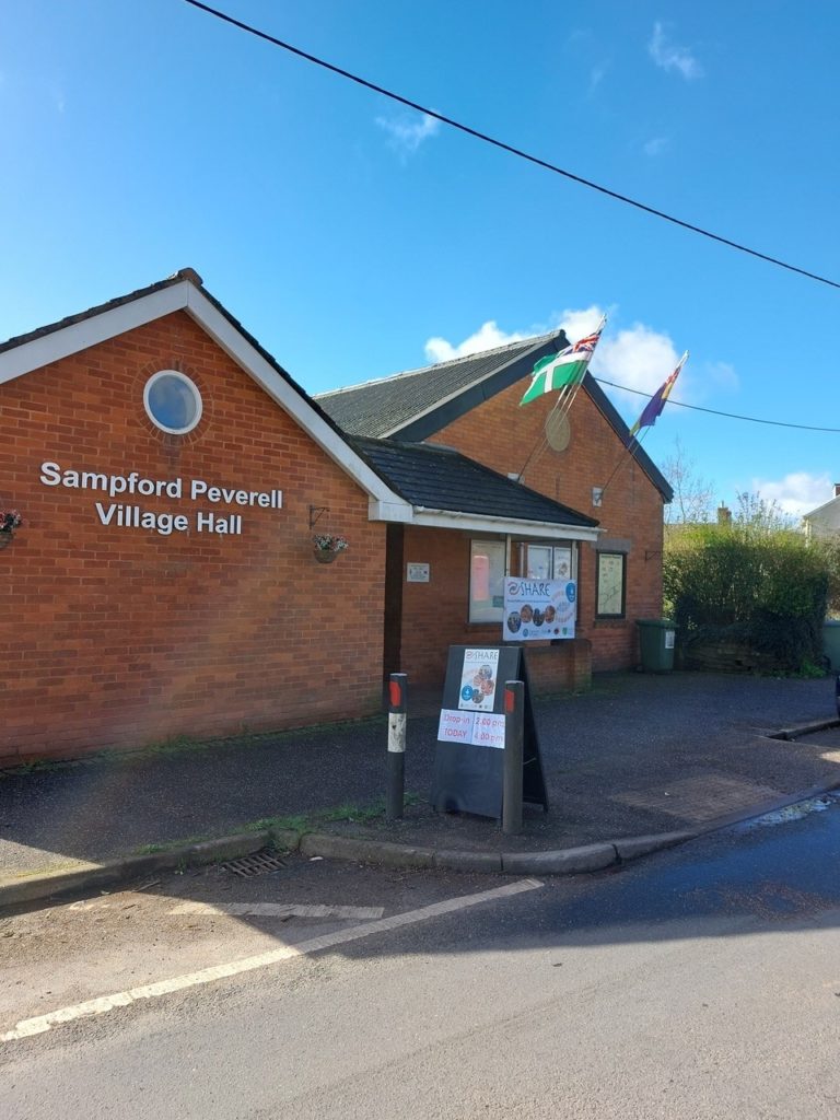 Photo of Sampford Peverell village hall with SHARE banners outside