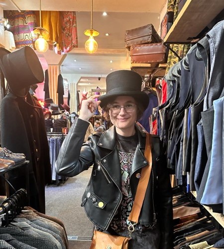 Student wearing a top hat in a vintage shop