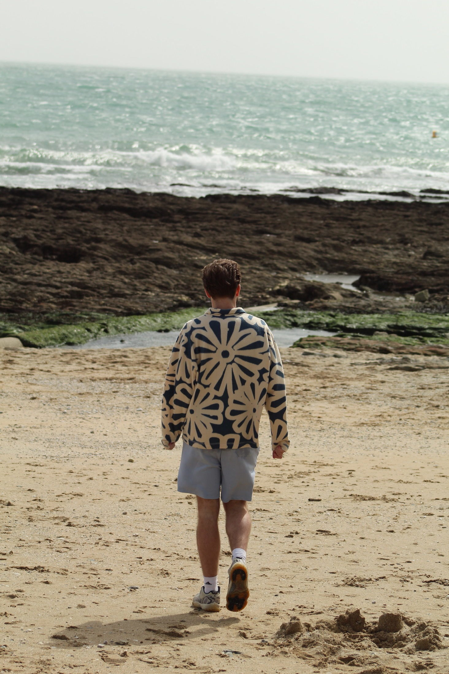 Student walking on the beach towards the sea