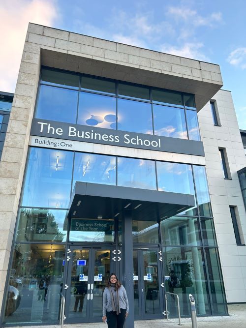 Student standing in front of the entrance to the Business School