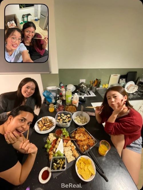 BeReal photo showing a group of friends eating a buffet style meal at a kitchen worksurface