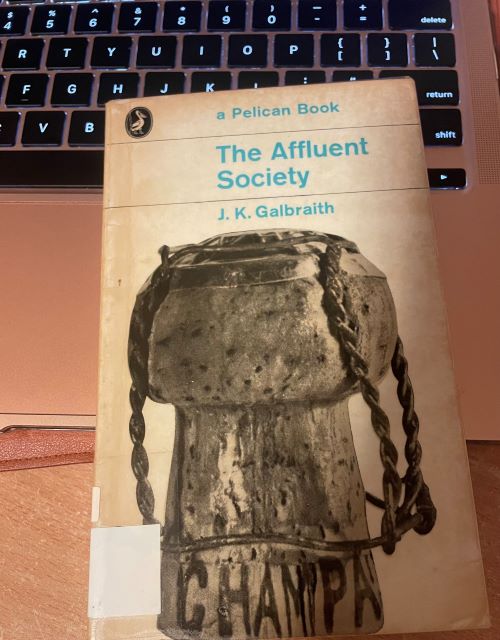 Old copy of the book 'The Affluent Society' resting on a laptop keyboard