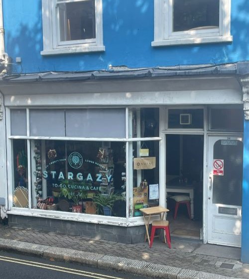 Front of Stargazy Cafe, which has a white-framed big window and open door underneath a bright-blue painted wall