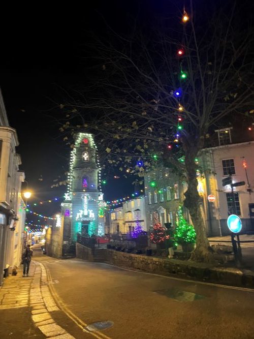 Old buildings in a town centre lit up at night with multicoloured Christmas lights