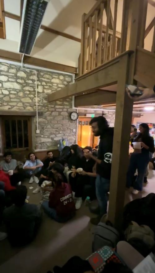 Students sat in a group on the floor in a cosy stone-walled room