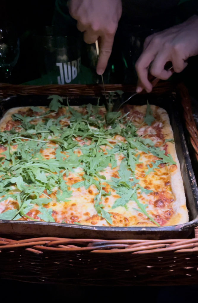 14" margarita pizza topped with rocket being cut