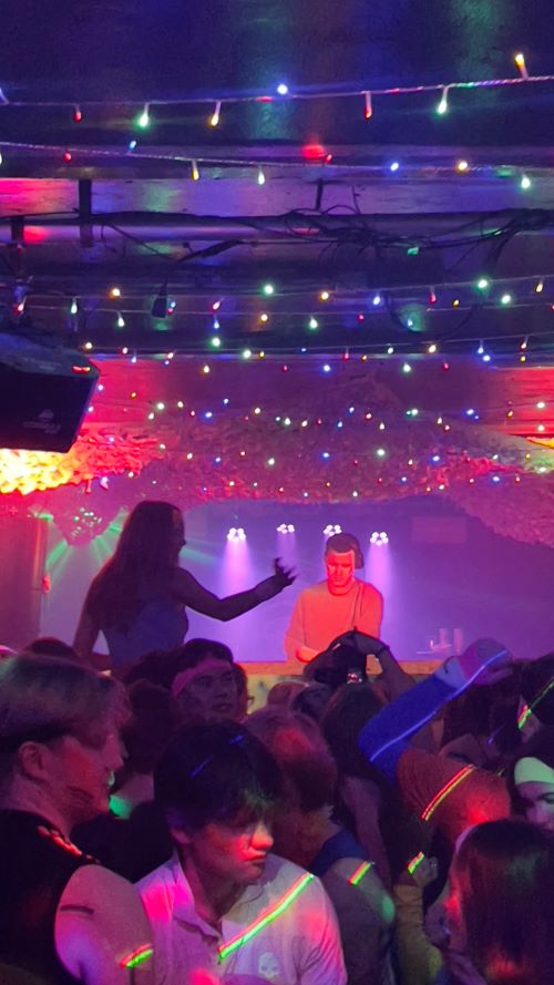 Busy night club with multicoloured lights and a DJ