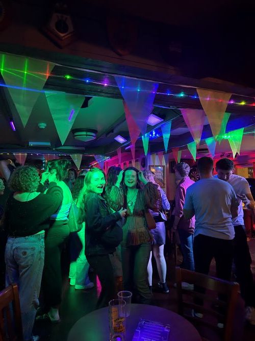 Students in a multi coloured lit nightclub