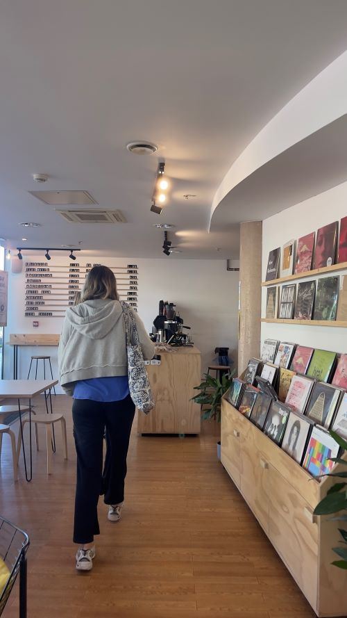 A student in a cafe with a wall of records on display