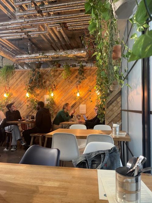 Cosy cafe with students sitting at tables next to a wood panelled wall