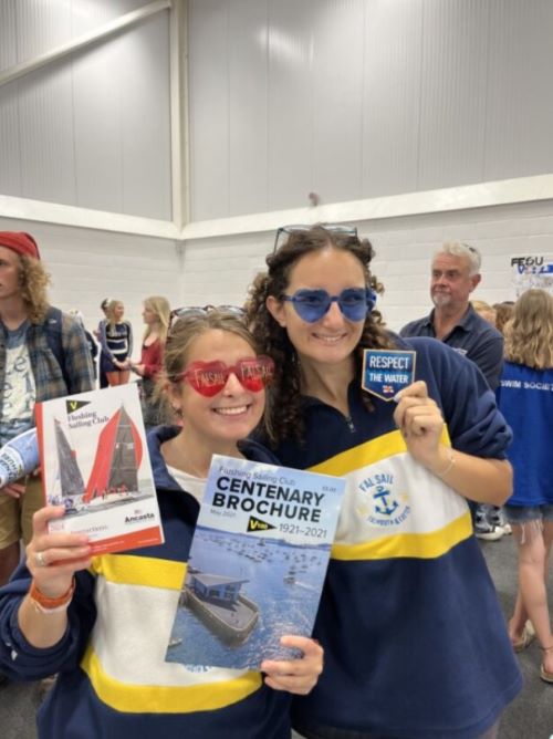 Two students wearing brightly coloured sunglasses and Fal Sail tops holding up flyers about sailing