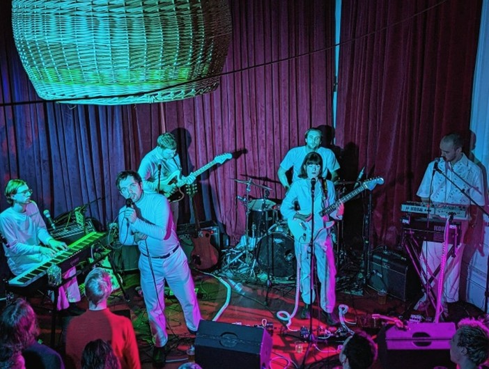 Band playing in front of dark red curtains