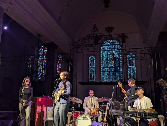 Band playing in front of stained glass windows