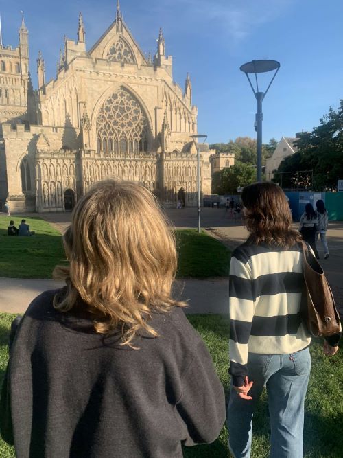 Two female students in front of Exeter Cathedral