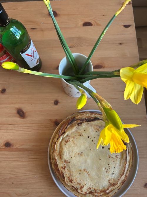 Pancakes on a table with a vase of daffodils
