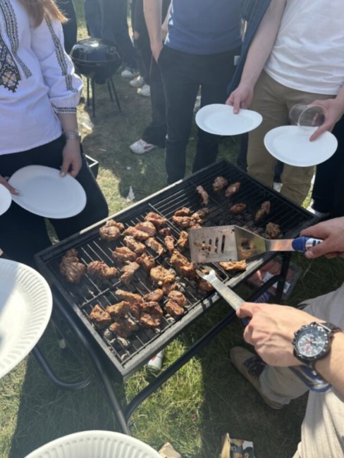 People gathered around a barbeque holding paper plates