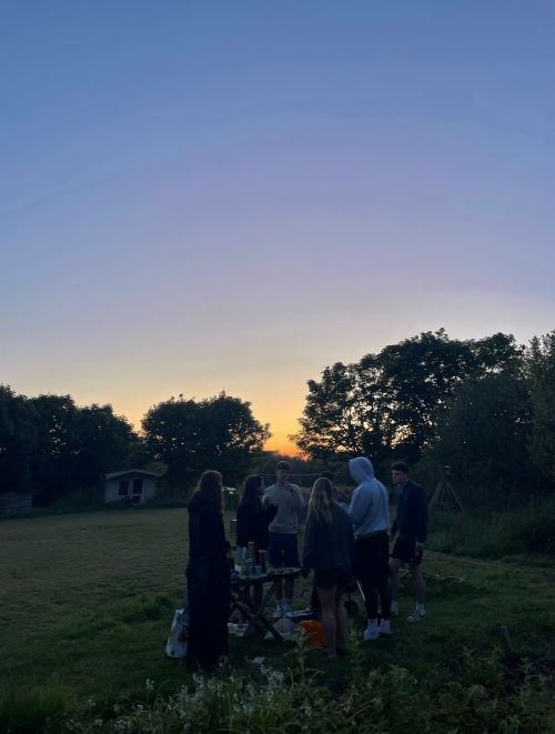 Group of students socialising outside in the sunset