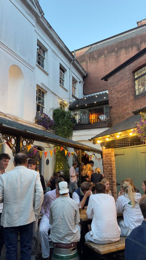 Pub patio surrounded by fairy lights full of students