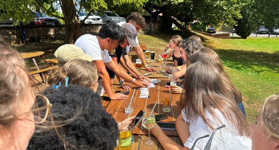 Students playing card games at a picnic table in the sunshine