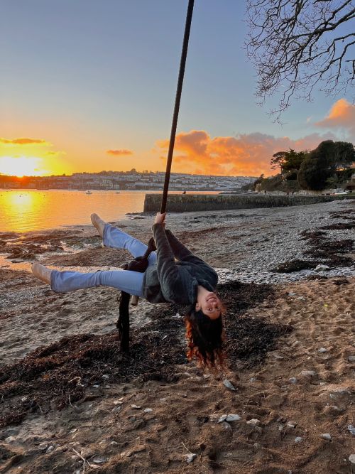 Female student on a beach rope swing in the sunset