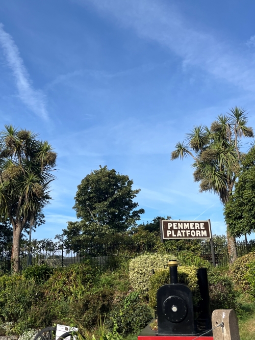 Sign for 'Penmere Station' between palm trees on a sunny day