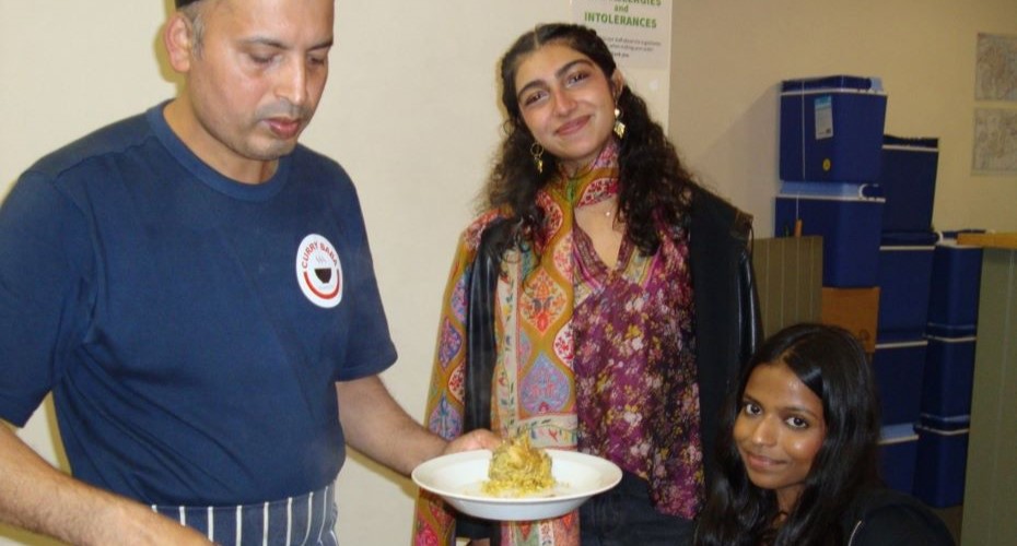 Two female Asian students being served food at Curry Baba in Falmouth