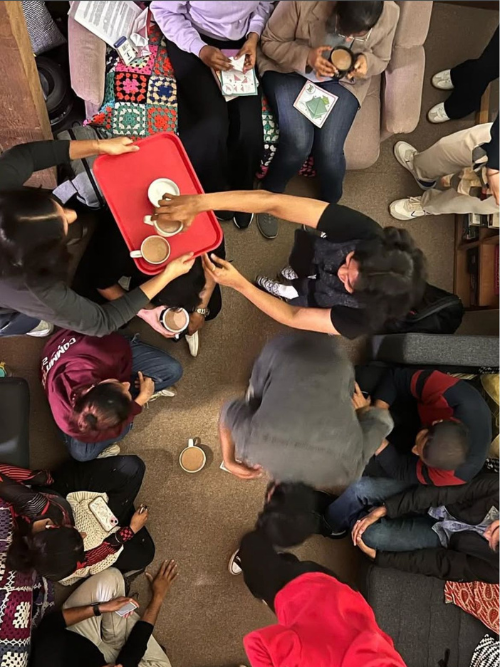An top-down photo of a large group of students drinking mugs of chai