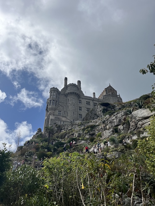 The castle on top of St Michael's Mount from below, with the green summer gardens 