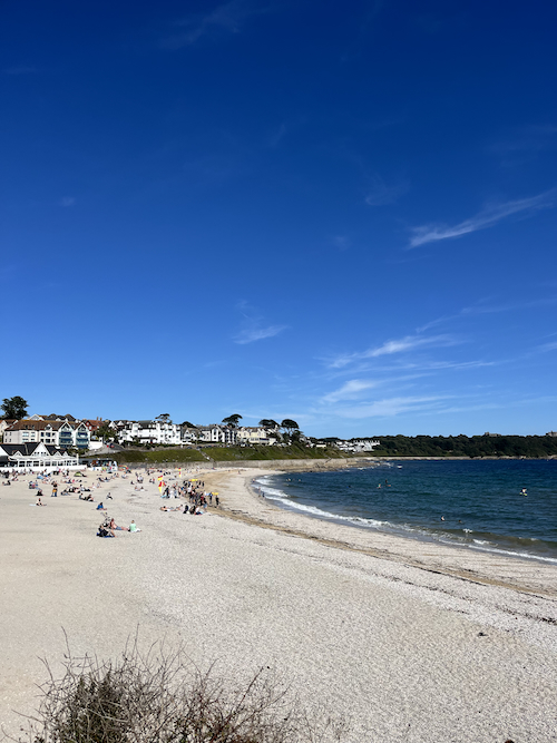 A sandy beach on a sunny day, with bright blue sea and skies