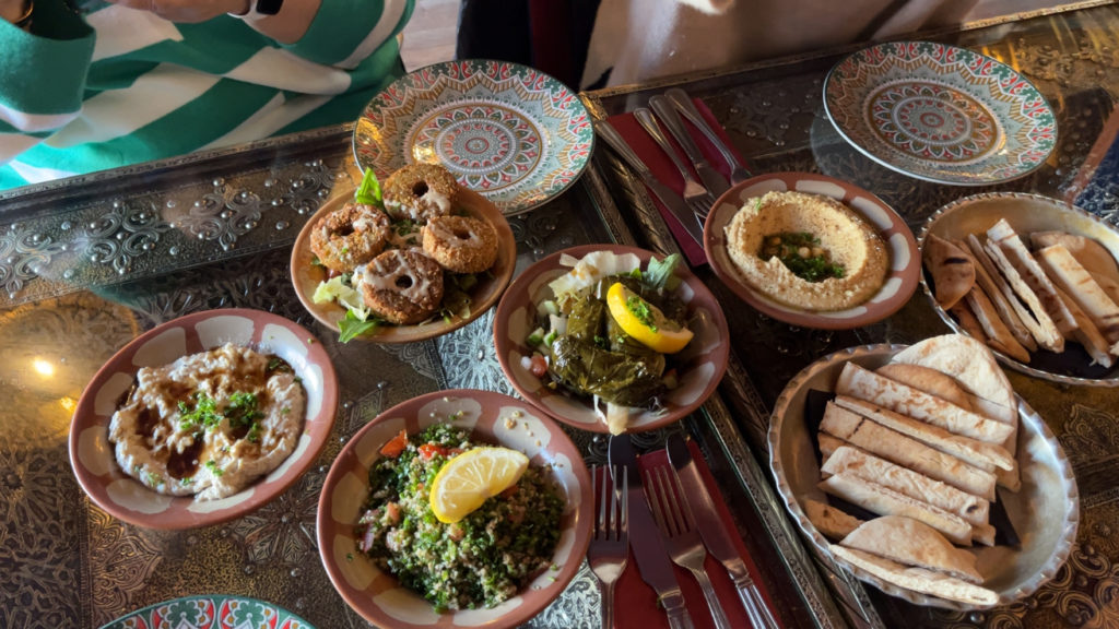 Several small dishes of different Moroccan foods served on a decorative glass table.