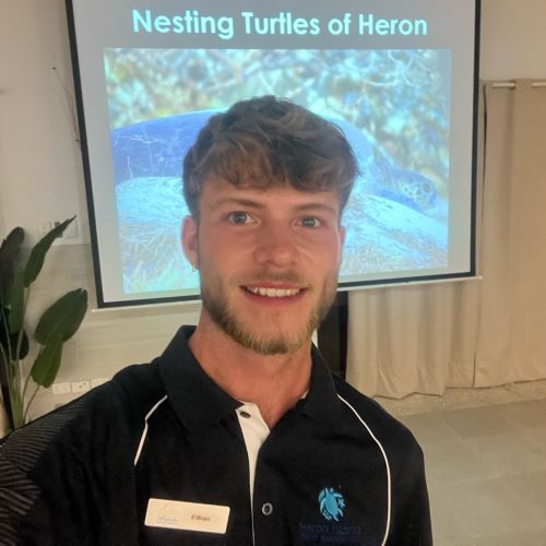 Photo of Ethan in front of a presentation screen about turtles