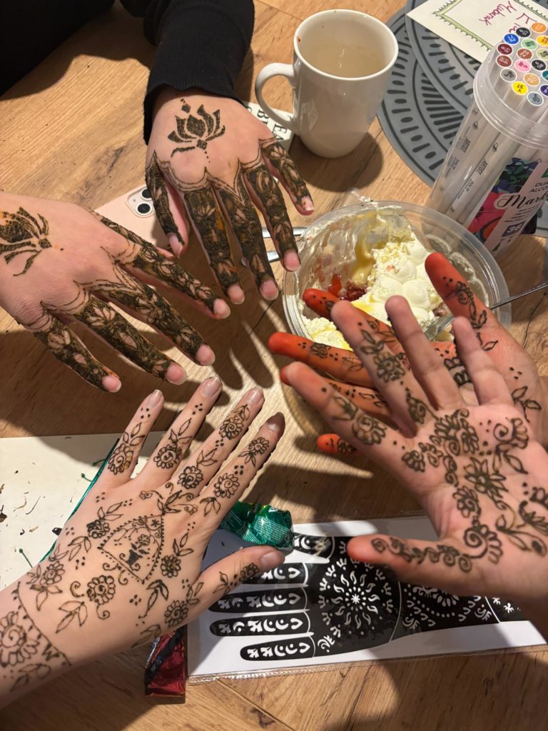 Several hands placed together which have been decorated with henna designs.